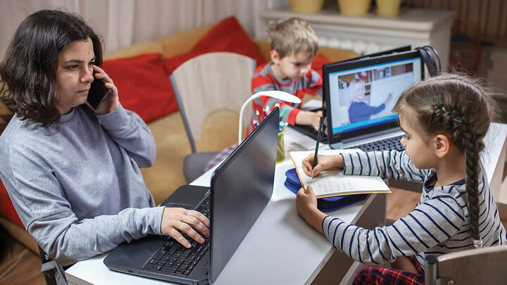 Students working on tests while teacher monitors them